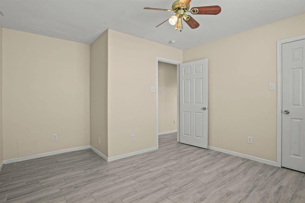 Room features ceiling fan and wood like tile flooring.