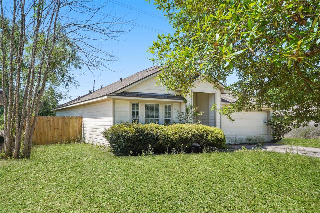 Charming single-story home with a welcoming front porch, lush greenery, and a spacious front yard. It features a two-car garage and a fenced side yard, perfect for privacy.