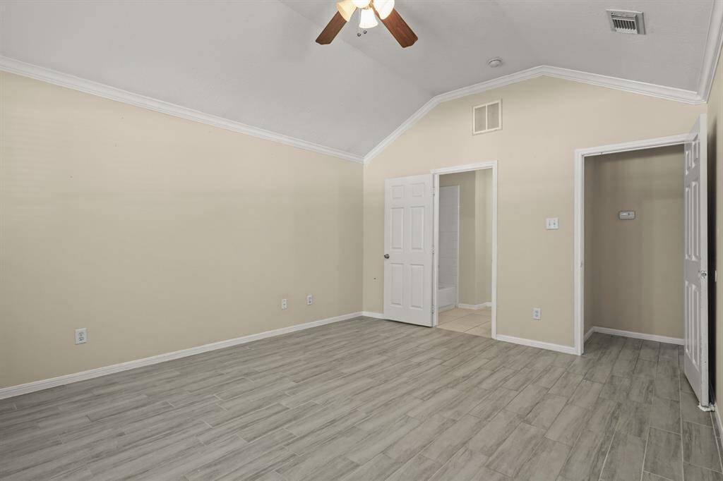 This room features vaulted ceiling with a ceiling fan and  wood-style tile flooring The space is bright and open.