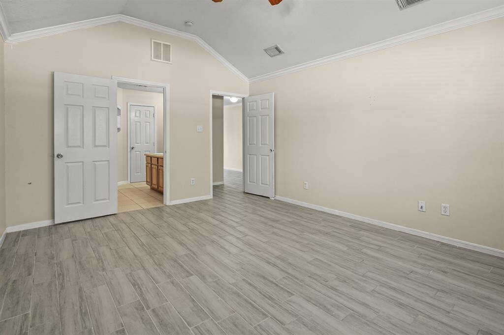 Primary bedroom features  wood-style flooring, crown molding and includes primary bathroom.