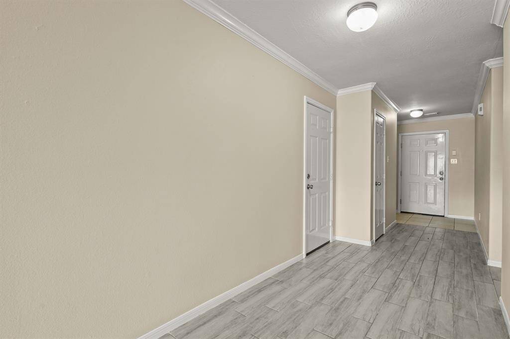 This photo features a well-lit hallway viewing the foyer/front door with tile flooring.