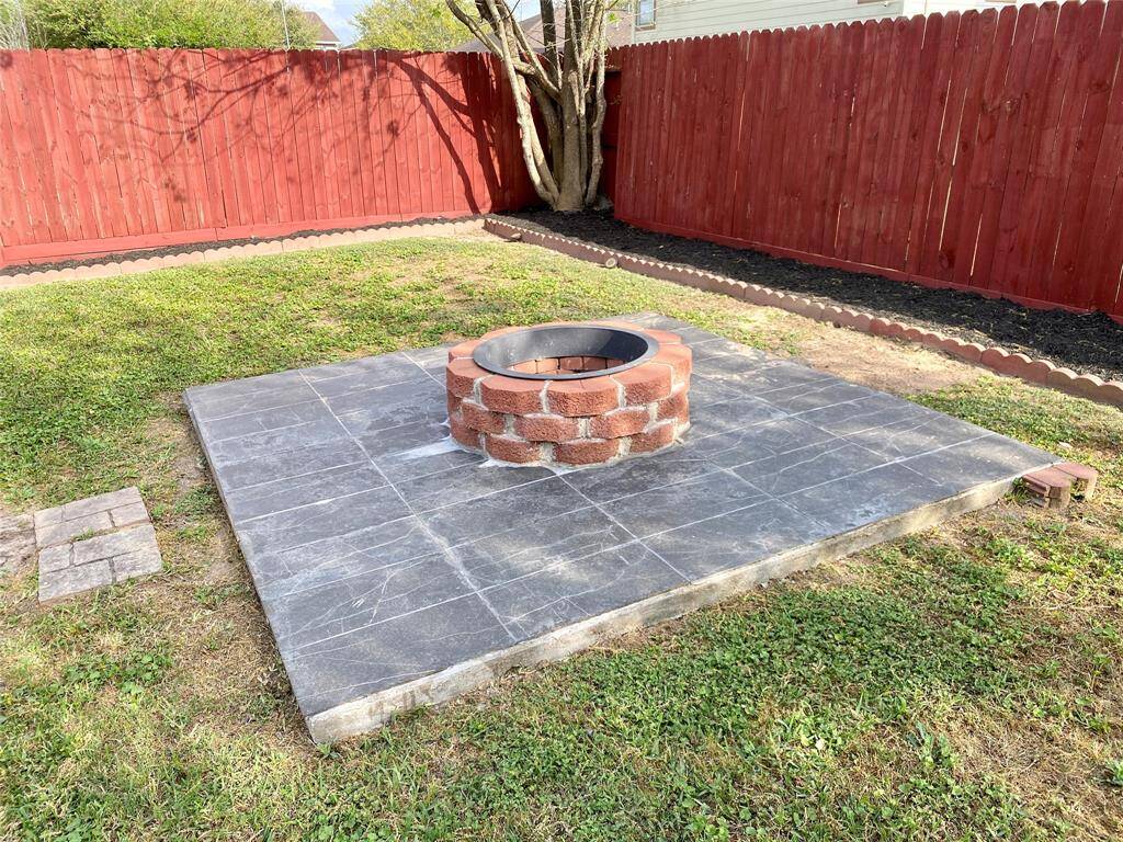 An additional tiled patio sits in the yard with a built in fire pit.
