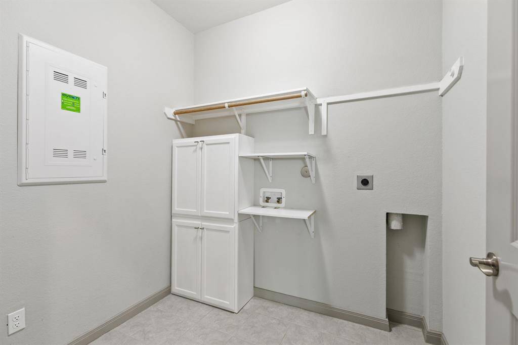 Utility room near primary bedroom has added shelves and cabinetry;  seller had a stackable washer/drawer.