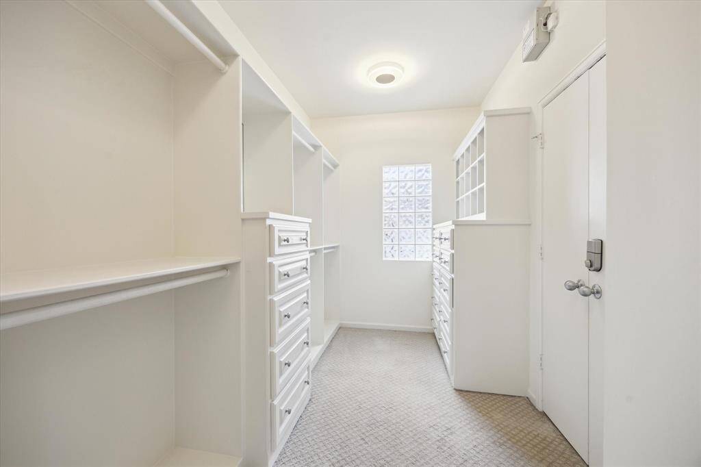 Primary walk-in closet (2nd one) with build-in drawers, shoe boxes, shelves, and hanging bars.