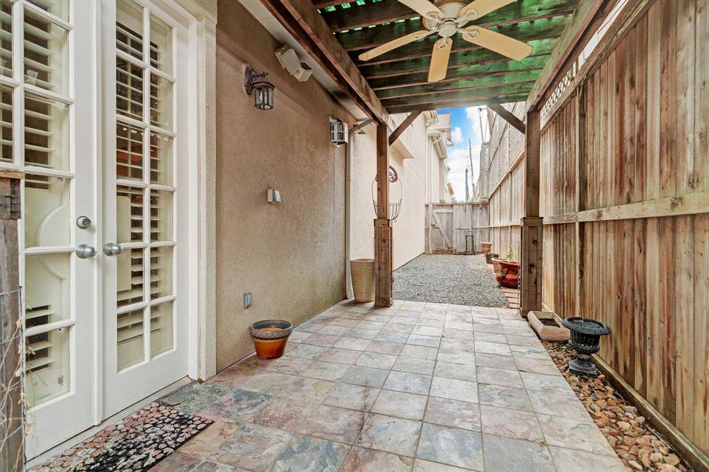 Covered patio with space for a small table and chairs and a grill. Great area to put potted plants, space for kids to play, and a dog run behind the patio to the left. It has speakers and a fan, with a cover overhead.