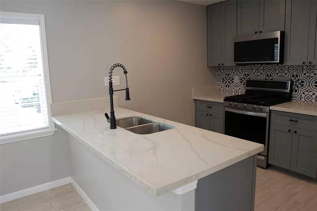 CONVINIENT BREAKFAST BAR WITH QUARTZ COUNTERTOPS TROUGH THE KITCHEN