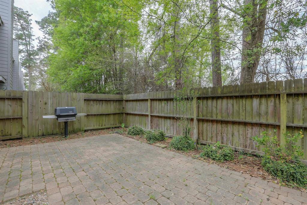 Enjoy a great view of the easy-maintenance patio pavers, featuring a naturally plumbed gas grill, and the added privacy of lush green space behind the property.
