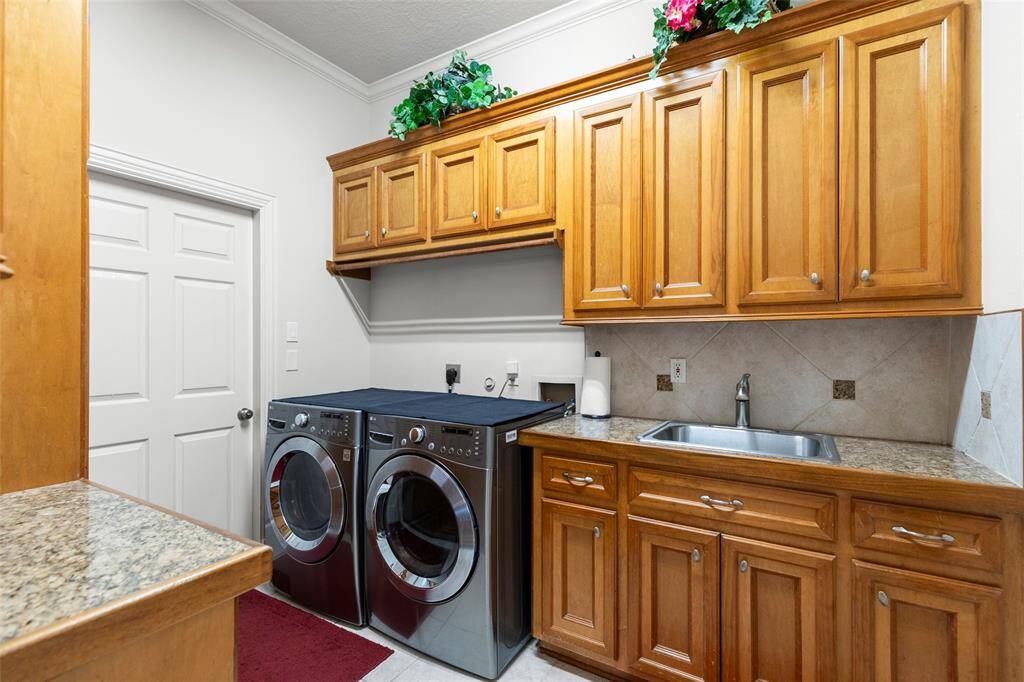 spacious laundry room with cabinets galore and separate sink