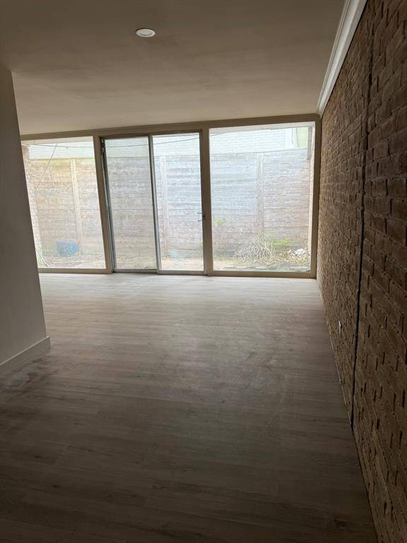 Exposed brick wall continues thru entire east wall, front to back. Large fenced patio off wall of glass doors invites outdoor natural light inside