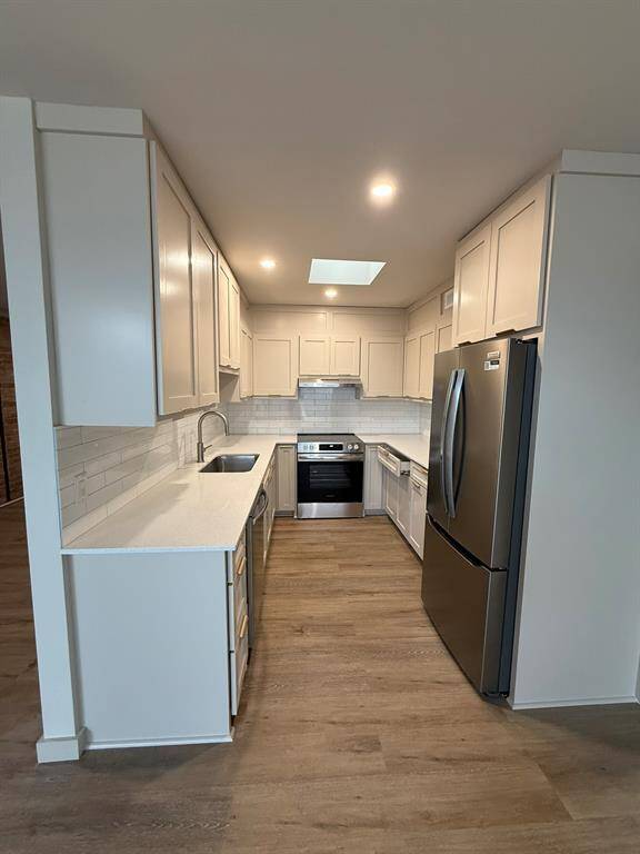 New kitchen with custom job built cabinets, French door refrigerator, recessed lighting and a sky light!