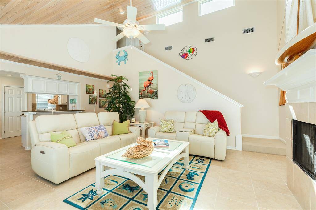 Living area with fireplace and mantle and addional high windows to welcome the sunlight