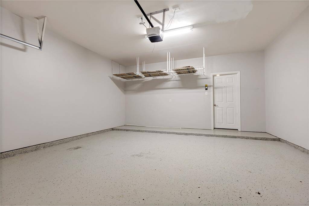 Garage with epoxy flooring, storage shelves on the ceiling.