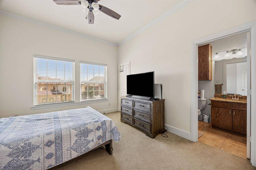 This light-filled bedroom offers generous dimensions, a ceiling fan, and plush carpeting, along with a private attached bathroom for added privacy and comfort.