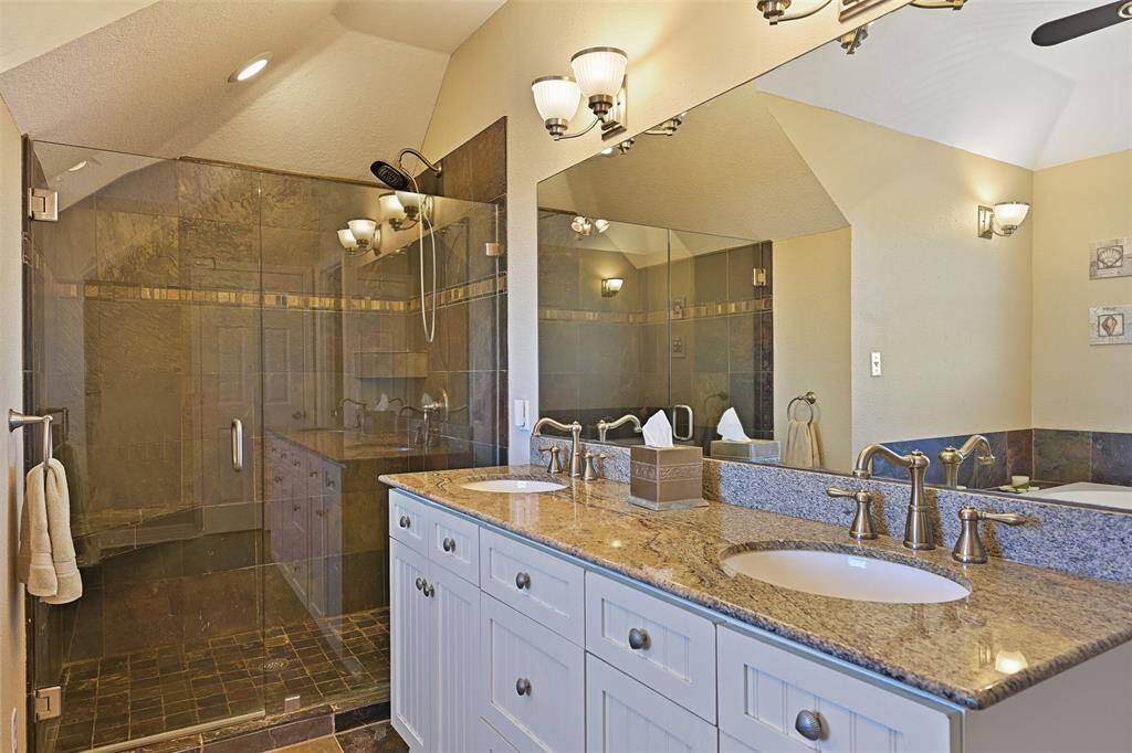 Double sink vanity with a spacious, modern shower.