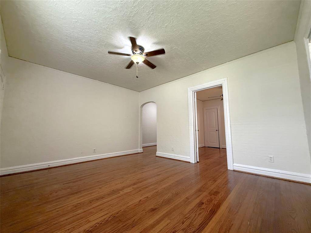 Beautiful hardwood flooring! Past the arched door to the left is the dining room. Past the door on the right is the side bedroom.