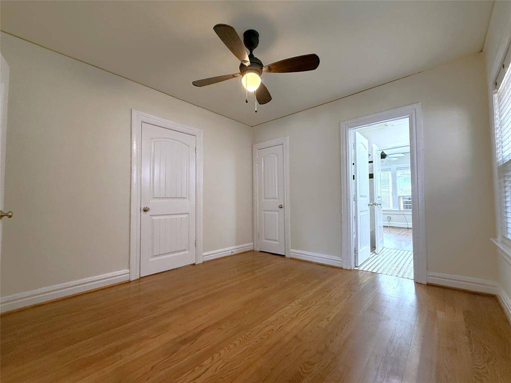 The side bedroom offers a ceiling fan/light. Past the open door on the right is the bathroom which is shared with the back bedroom.
