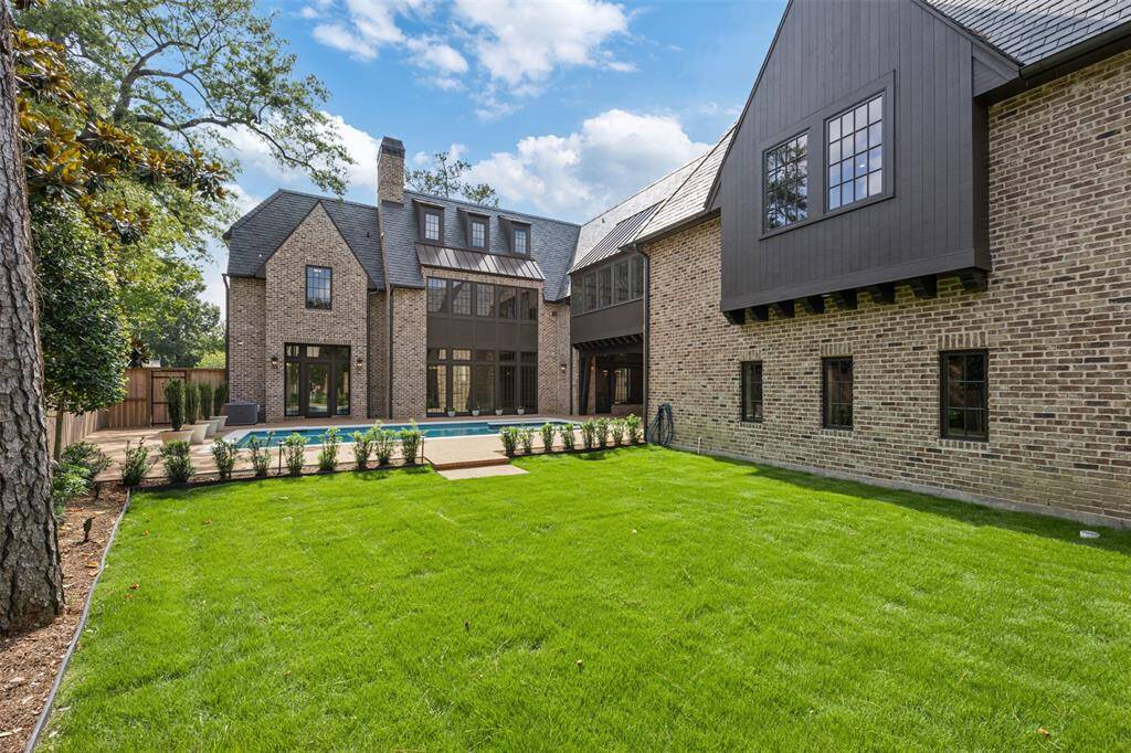 Bask in year-round comfort beneath the dramatic beamed ceiling of this covered terrace, where a gas fireplace and oversized ceiling fan set the tone for elegant outdoor living. With views of the pool and direct access to the kitchen and dining areas, this space is designed for seamless indoor-outdoor entertaining.
