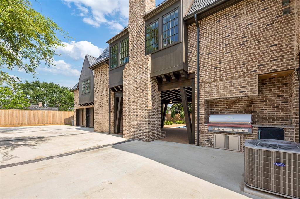 Tucked just off the covered patio, this outdoor kitchen features a built-in grill set into classic brickwork—perfect for effortless al fresco cooking. With generous driveway space nearby and seamless access to the pool area, this setup blends function and flow for elevated outdoor entertaining.