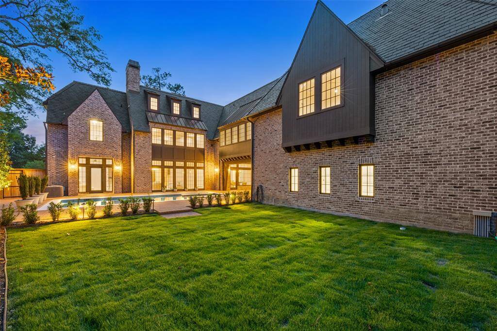 This expansive driveway leads to a trio of rich, wood-tone garage doors that blend beautifully with the brick exterior, offering both function and architectural elegance. Whether you’re hosting guests or arriving home after a long day, this private motor court sets the tone for luxury living.