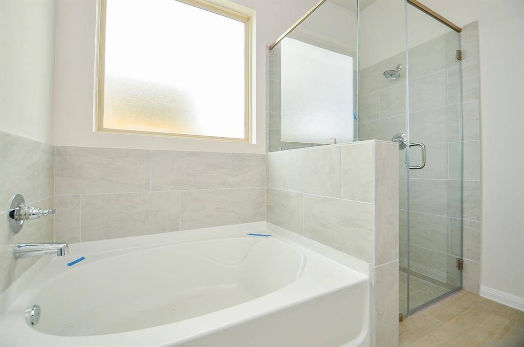 It features a luxurious soaking tub with a separate glass-enclosed shower.