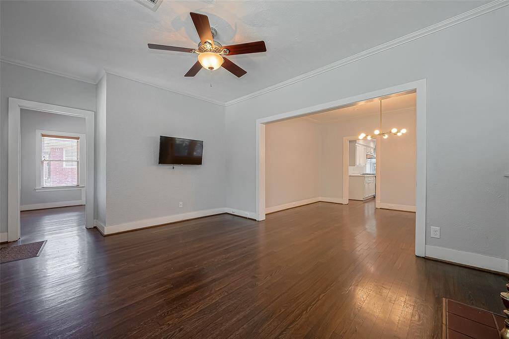 This kitchen features sleek white cabinetry, quartz countertops, and a modern black refrigerator. It has hardwood flooring, ample storage, and bright lighting, creating a contemporary and inviting space.