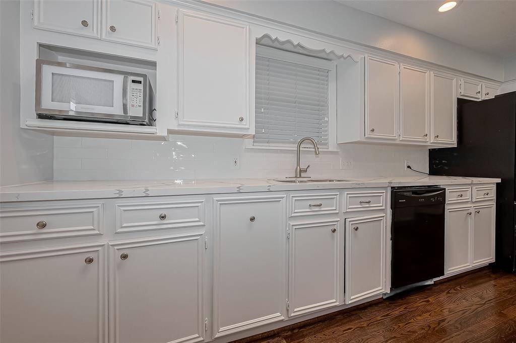 This room features a spacious dining area with rich hardwood floors, built-in cabinetry, and large windows for natural light. A modern chandelier adds elegance, while the adjacent kitchen offers stainless steel appliances and a bright, open layout.