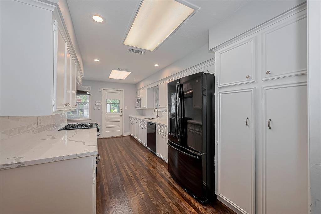 Bright and spacious room with hardwood floors, large windows with blinds, and a ceiling fan. Ideal for a bedroom or office space.