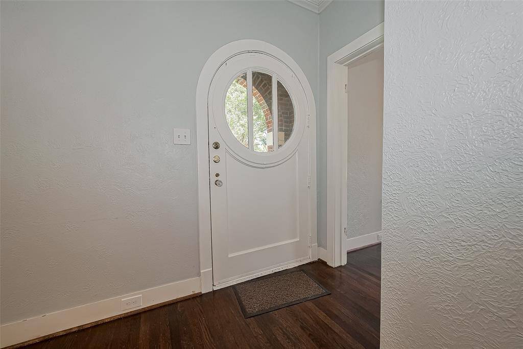Bright kitchen with white cabinetry, hardwood floors, and large window offering natural light. Includes a door to the outside and built-in microwave.
