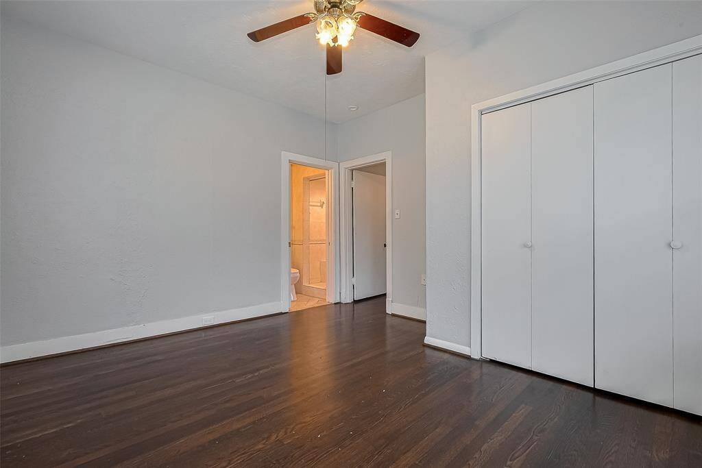This room features polished hardwood floors, light gray walls, and a ceiling fan, with two white doors offering storage or access options.