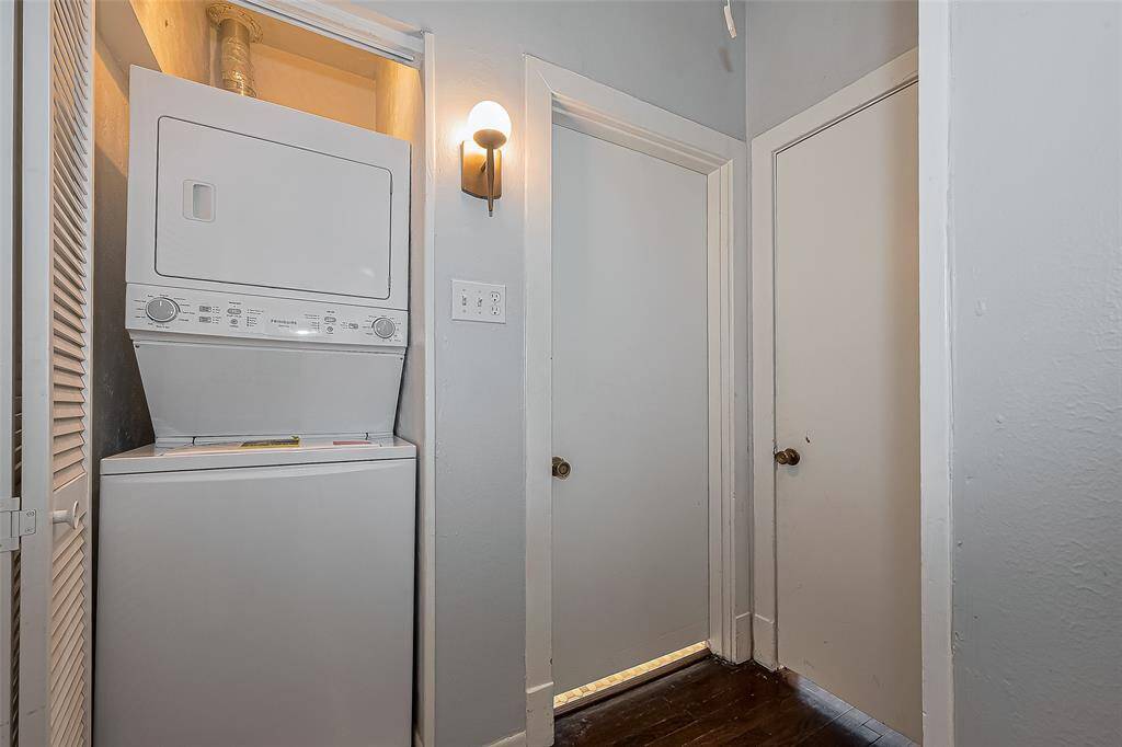 This kitchen features sleek black appliances, including a refrigerator and dishwasher, complemented by white cabinetry. The space is well-lit with recessed lighting and offers ample storage, with a classic wood floor adding warmth.