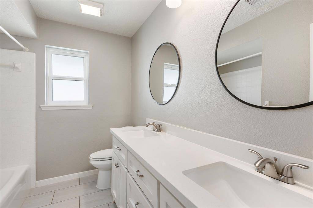 Secondary bathroom featuring double sinks and beautiful natural light.