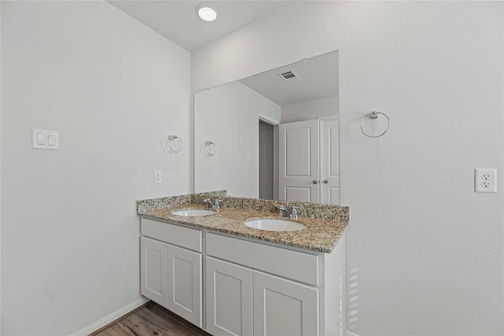 The primary bathroom features aspacious vanity with shaker-stylecabinetry, sleek granite countertops,dual sinks, and sophisticated nickelfinishes.