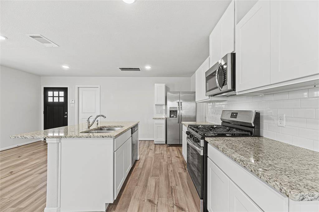 The open-concept kitchen boastssleek granite countertops, a classicwhite subway tile backsplash, and afunctional island with a double-basinsink. A gas range, paired with amatching overhead microwave,completes this stylish and efficientspace.