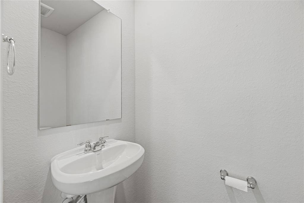 The conveniently located downstairspowder room features light, neutralpaint, a classic pedestal sink, andelegant nickel finishes for a stylishtouch.