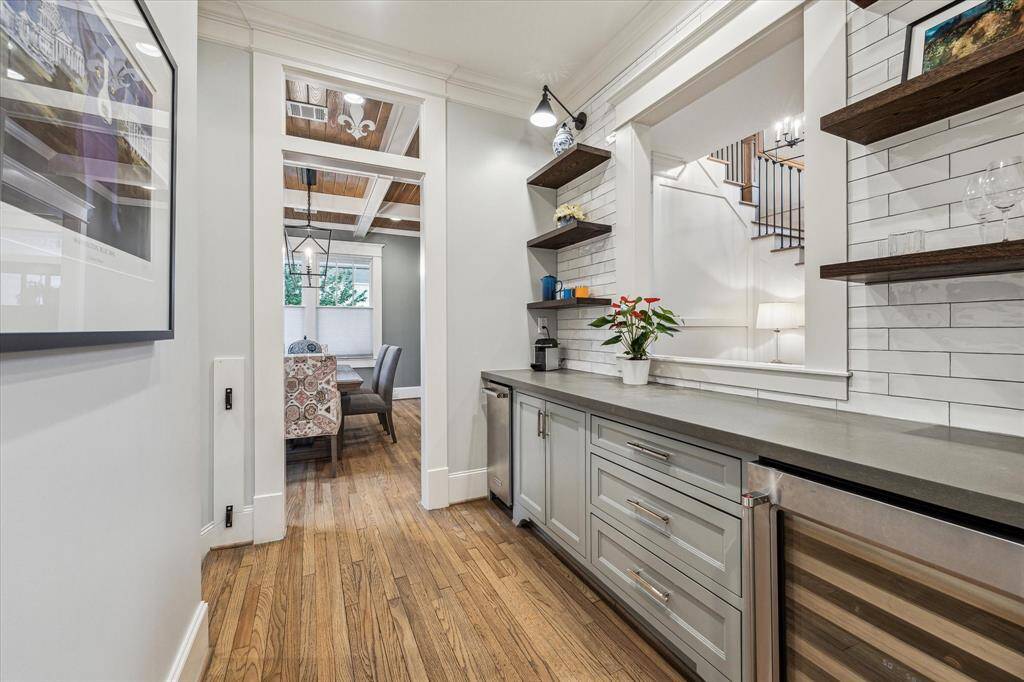 elegantly designed butler's pantry, seamlessly blending functionality and style. This sophisticated space boasts high-end quartz countertops and custom light gray cabinetry, providing ample storage for all your kitchen essentials. The built-in ice maker and beverage fridge are perfect for entertaining, ensuring your guests' drinks are always chilled and ready.