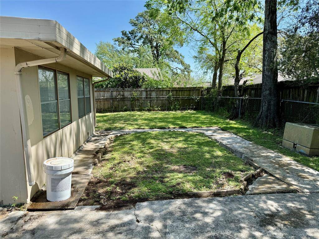 Tranquil fenced backyard featuring a spacious concrete patio and lush grass area, perfect for relaxation and entertainment.