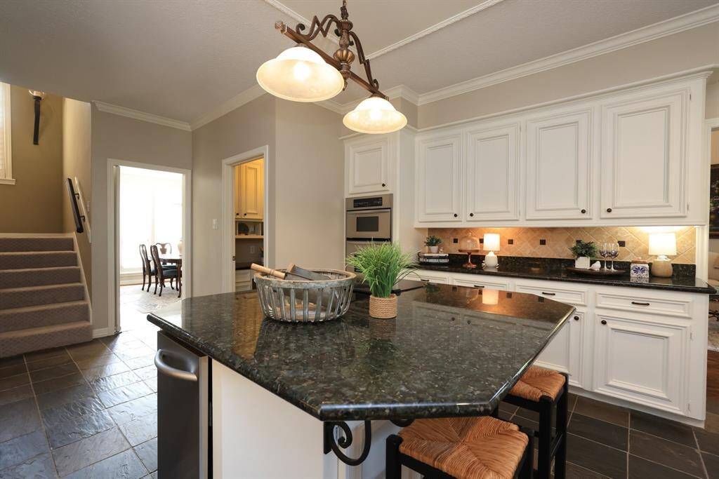 The kitchen has slate floors and great storage in the island with the sun room in view.