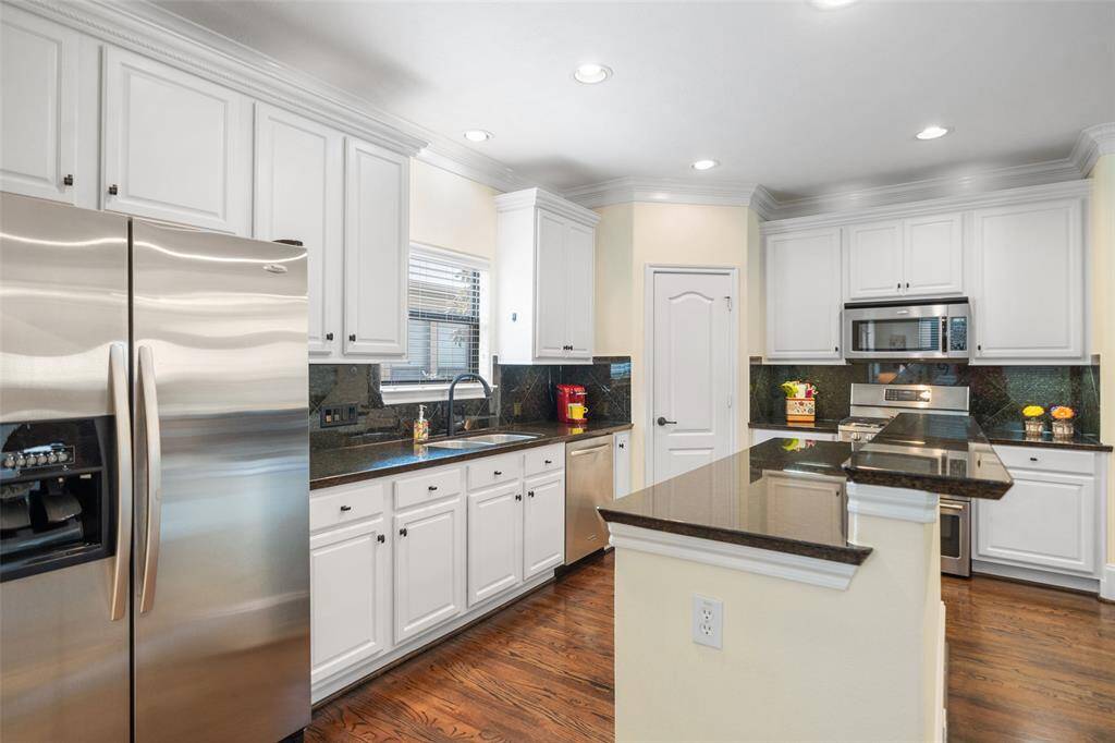 This kitchen features a central island with a breakfast bar, updated white cabinets, and modern stainless steel appliances