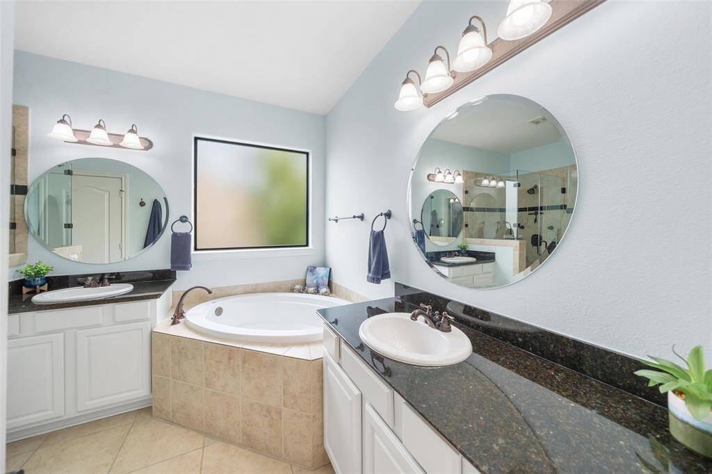 The primary bath features dual vanities and a large soaking tub, creating a spacious and relaxing retreat. The frosted window adds an extra layer of privacy while allowing natural light to fill the space.