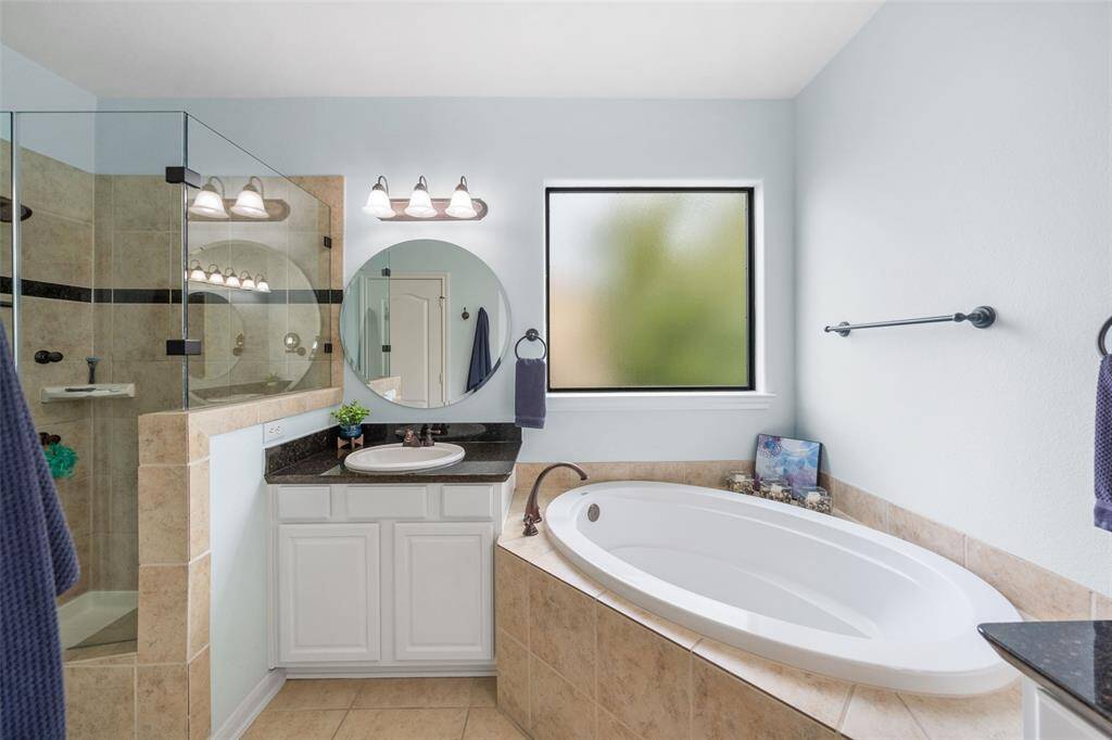 The primary bath also features a frame-less walk-in glass shower, offering a sleek and modern design for a luxurious bathing experience.