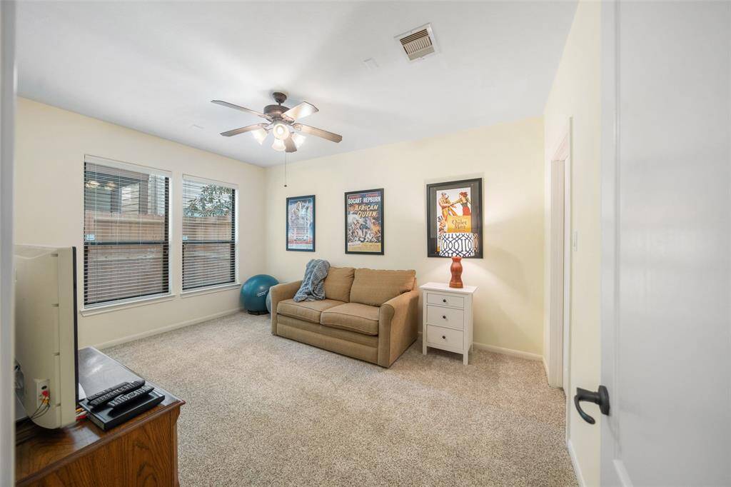 Currently being used as an additional living space, this bedroom on the first floor features plush carpet, a walk-in closet, and views into the backyard.