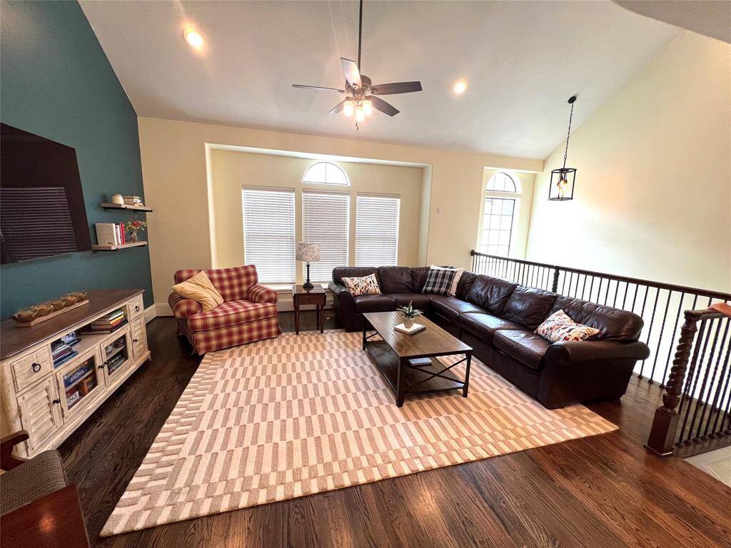 The living room features large windows that face out toward the community, bringing in natural light. High ceilings and an open floor plan enhance the airy, bright feel of the space.