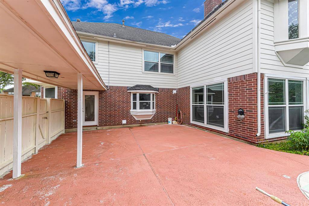 This photo showcases a spacious outdoor patio area with brick and siding exterior, featuring large windows for natural light. The area is partially covered, providing a versatile space for outdoor activities or relaxation.