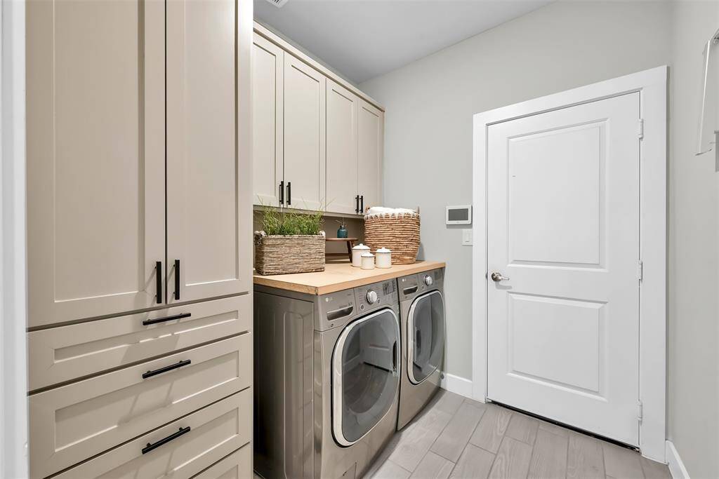 Spacious laundry room with custom cabinets, additional storage, and direct garage access.