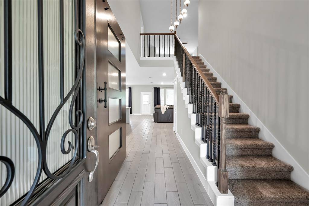 As you step inside, you’re greeted by a spacious foyer with light gray wood-look tile flooring that stretches throughout the open area.