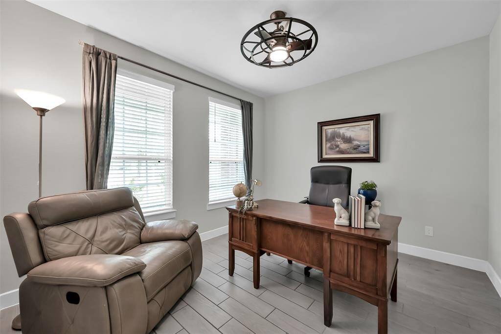 This inviting office, located to the left of the front entry, showcases a modern design with light gray tile flooring and soft neutral walls. The space is brightened by two large windows overlooking the front, allowing ample natural light to enhance productivity.