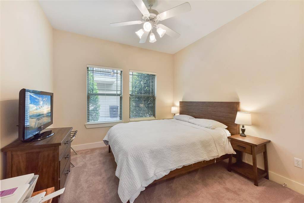 Clean, bright downstairs guest bedroom suite with windows overlooking back of property, plus custom blinds, ceiling fan and carpet.