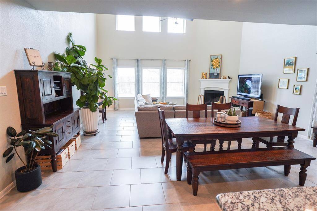 This spacious living area features high ceilings, abundant natural light, and an open layout. It includes a cozy fireplace, a dining area that is perfect for family gatherings. Large windows and tasteful decor add warmth and charm.