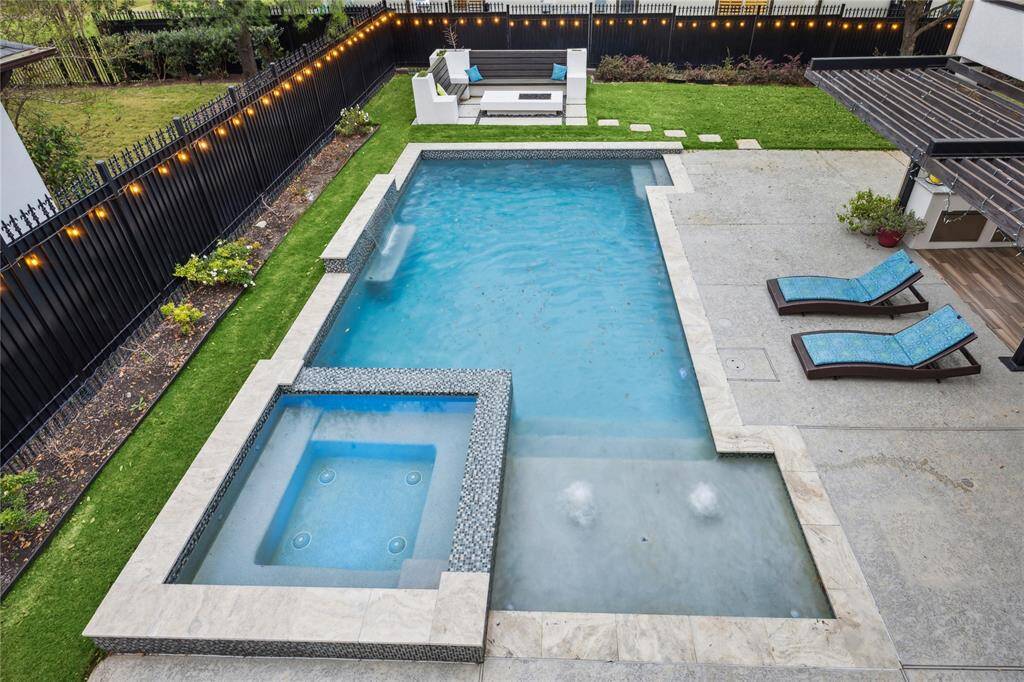 Anchoring the end of the stunning pool is a grand fire pit, framed  by a curved built in seating area.  Perfect for cozy evenings under the stars or entertaining guests in style.