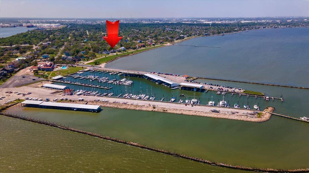 This aerial photo showcases a picturesque waterfront location with a marina full of boats, a scenic coastline, and lush greenery. Ideal for water enthusiasts and those seeking serene views.